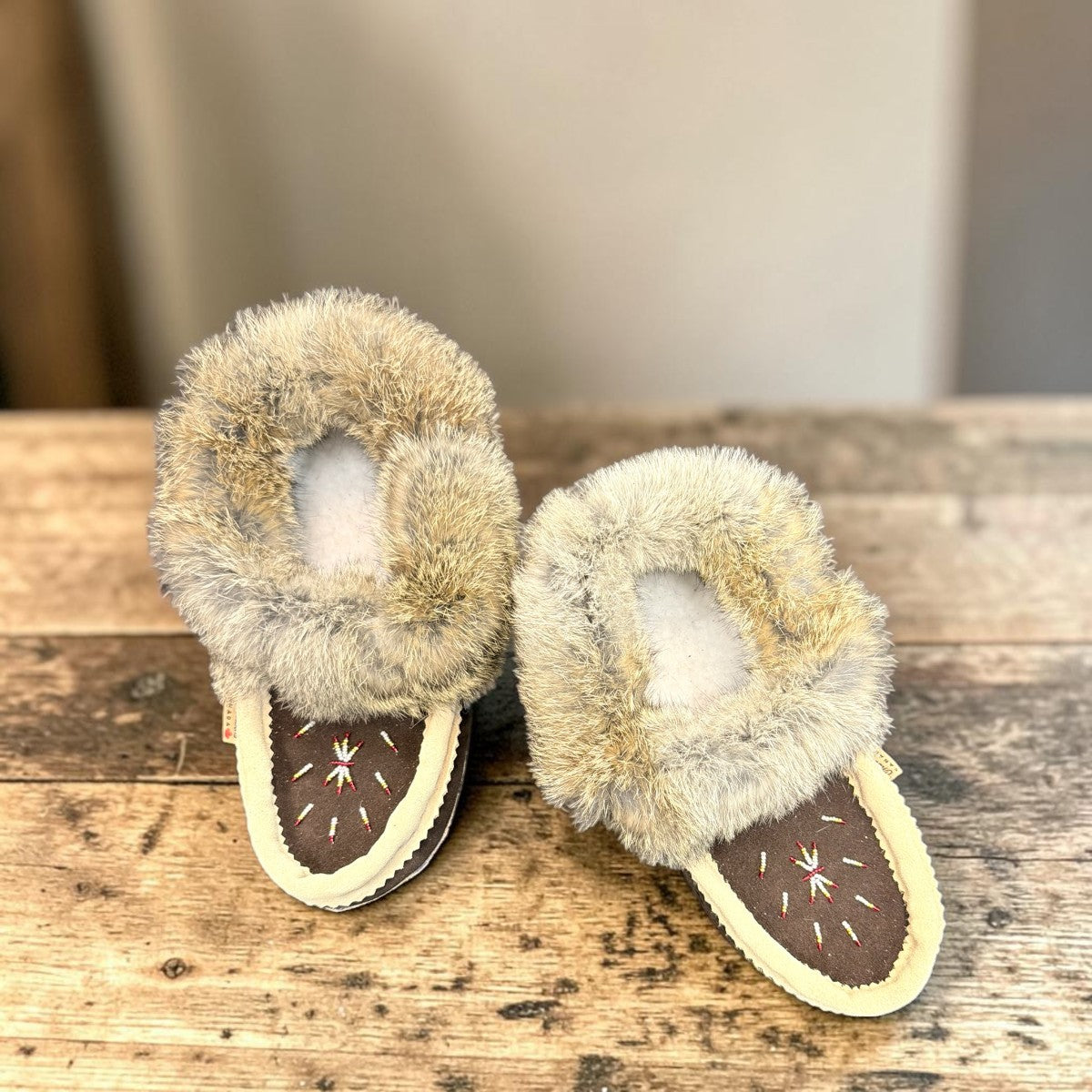 Alberta brown suede moccasin with cream trim and fluffy rabbit fur ankle collar, side view. Photo of upper view.