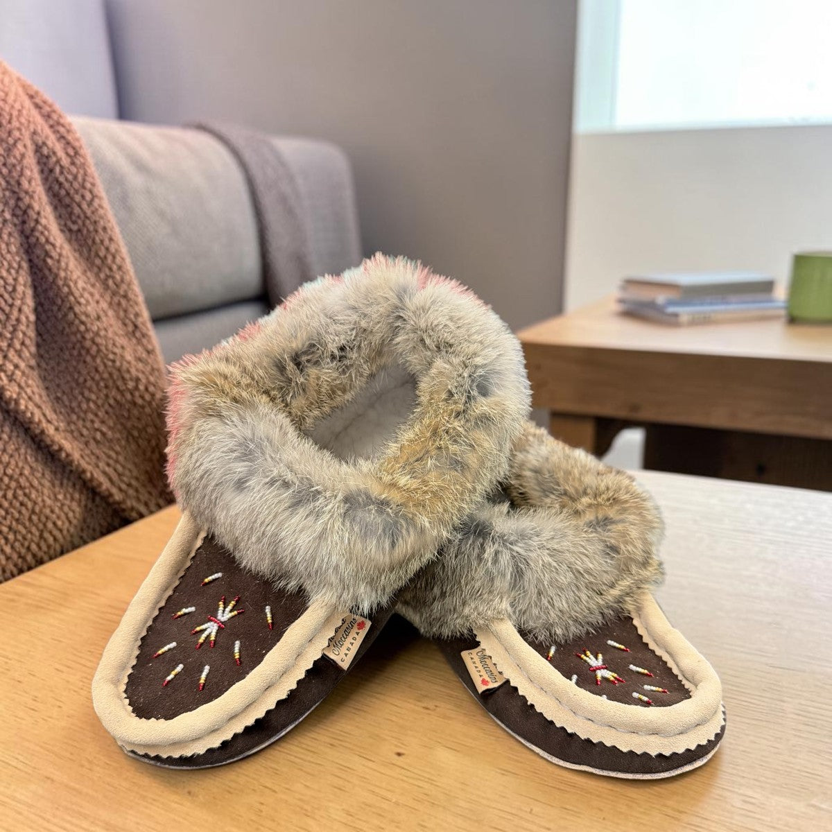 Alberta brown suede moccasin with cream trim and fluffy rabbit fur ankle collar, side view. Photo of front side view.