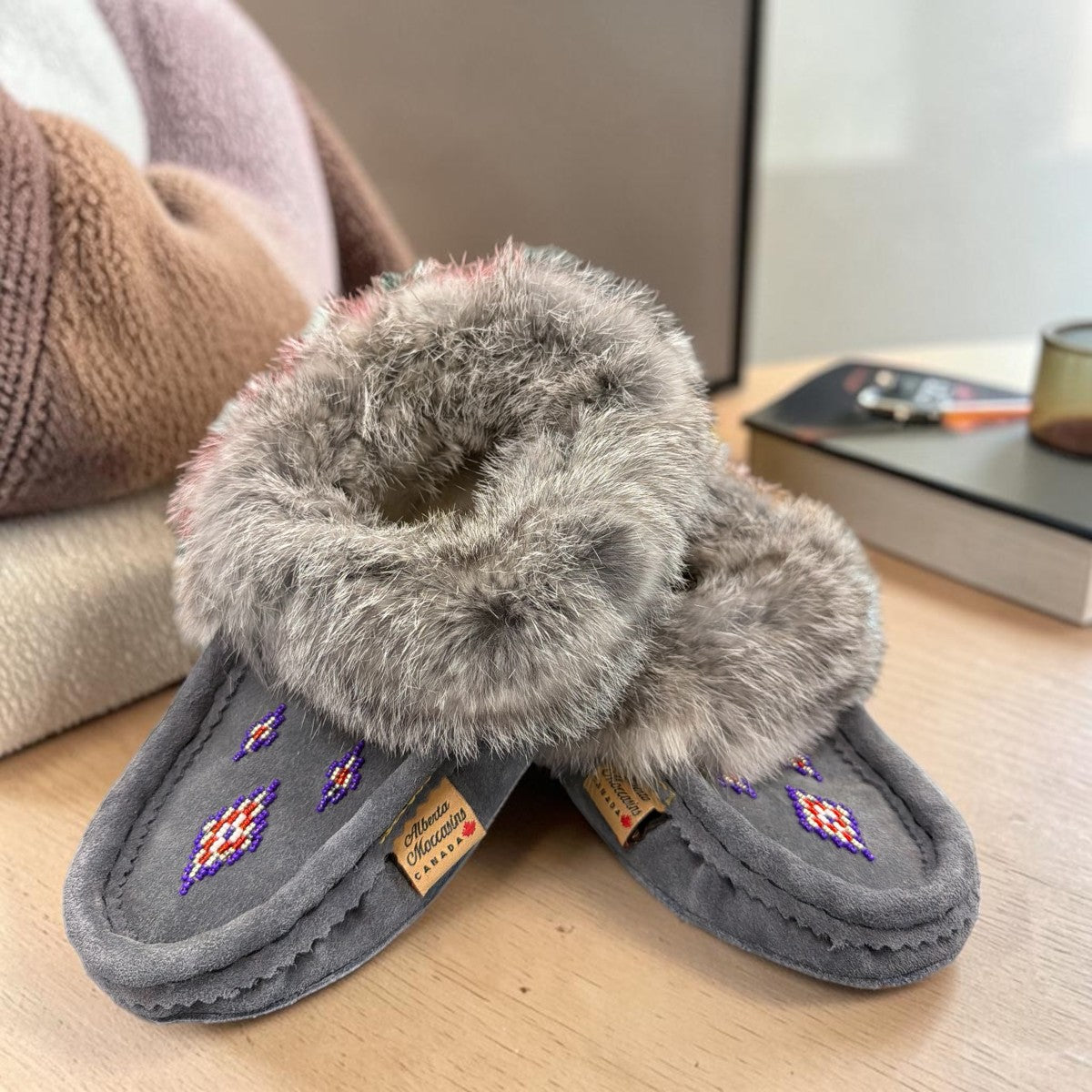 Alberta dark grey suede moccasins with a plush rabbit fur ankle collar, handcrafted for comfort. Photo of front side view.