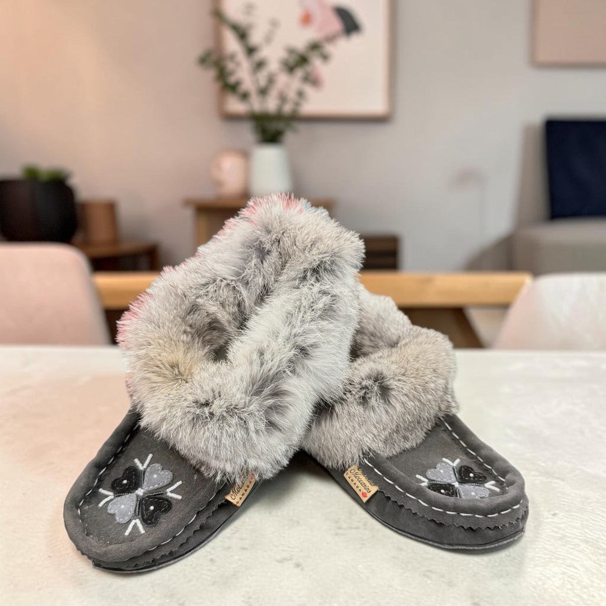Alberta grey suede moccasins with a plush rabbit fur ankle collar and hand-stitched detailing. Photo of front side view.