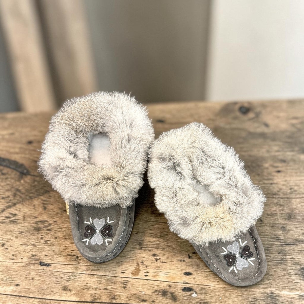 Alberta grey suede moccasins with a plush rabbit fur ankle collar and hand-stitched detailing. Photo of upper view.