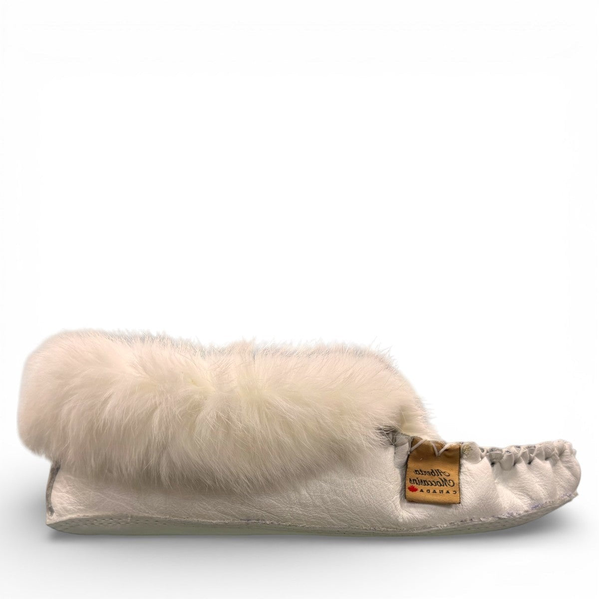 Alberta  white leather moccasins featuring a plush fur collar and side brand tag, side view.
photo of the right side