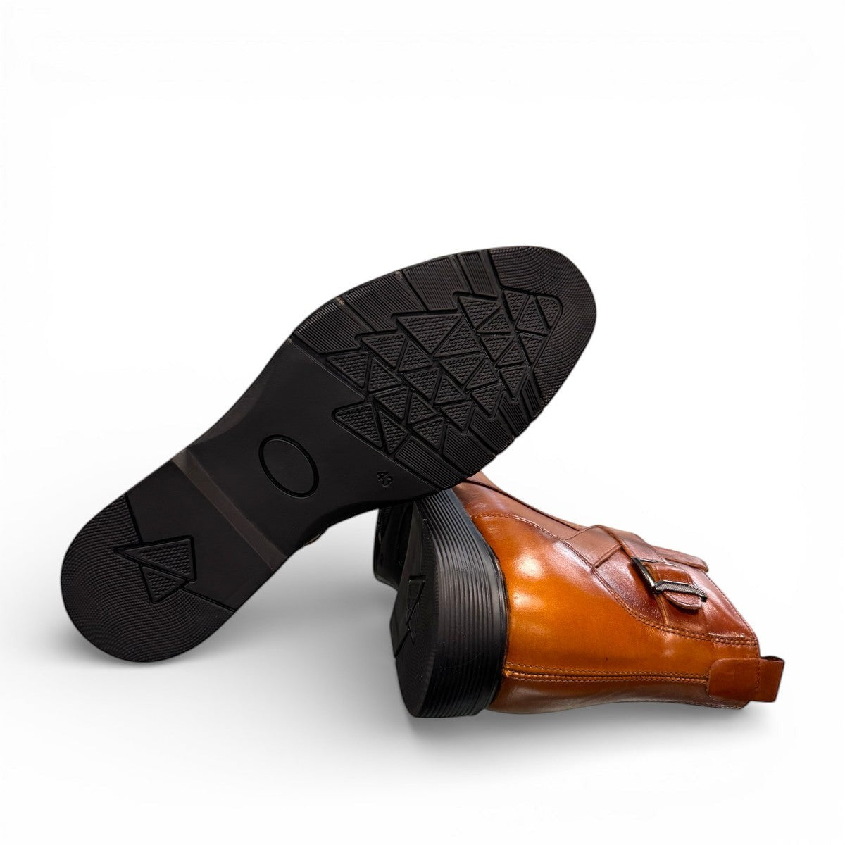 Brown leather ankle boots with a side buckle strap and durable rubber sole for formal wear. Photo of bottom view.