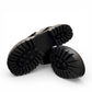 Django & Juliette black leather platform sandals featuring an oversized bow and chunky lugged sole. Photo of bottom view.