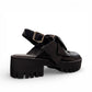 Django & Juliette black leather platform sandals featuring an oversized bow and chunky lugged sole. Photo of back side view.