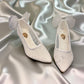 NIKPA SANA white bridal pump with glitter finish, pointed toe, and sheer tulle bow detail on the heel.