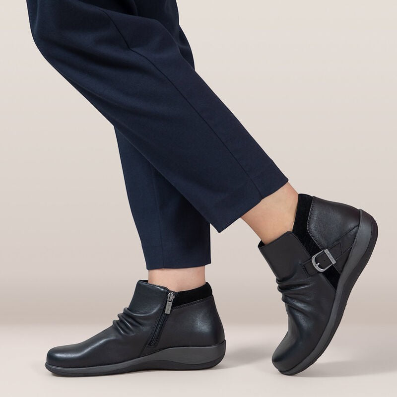Aetrex Luna black leather ankle boots with pleated detail, side zipper, and adjustable buckle.