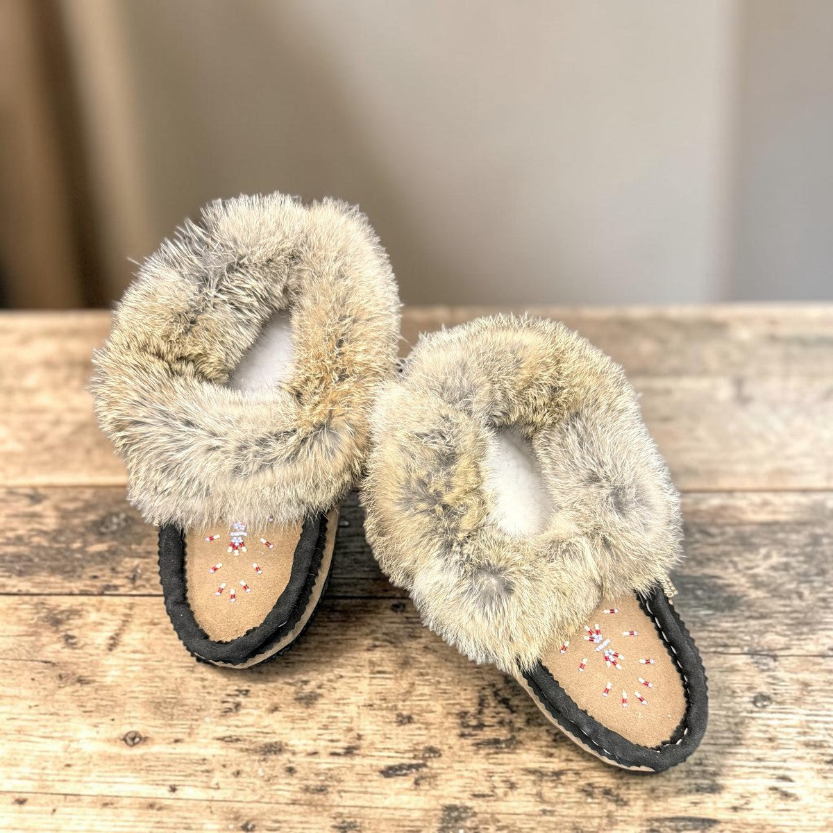 Alberta suede moccasins in coffee and black with a plush rabbit fur ankle collar and side stitching. Photo of upper view.