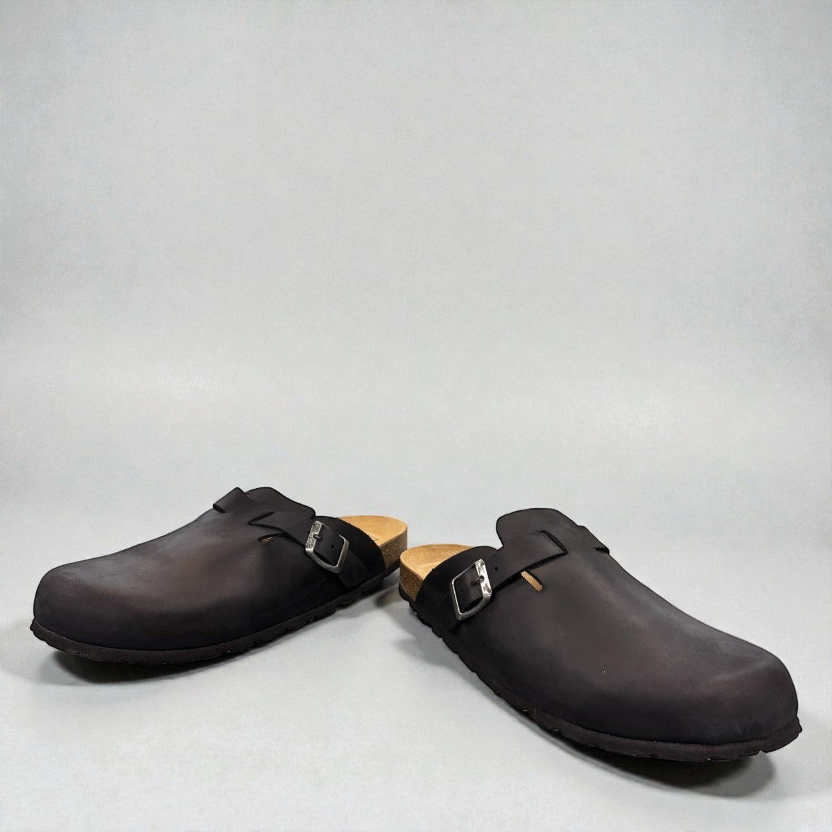 Biotime Burly black leather clogs showing the textured EVA outsole and cork footbed from below.