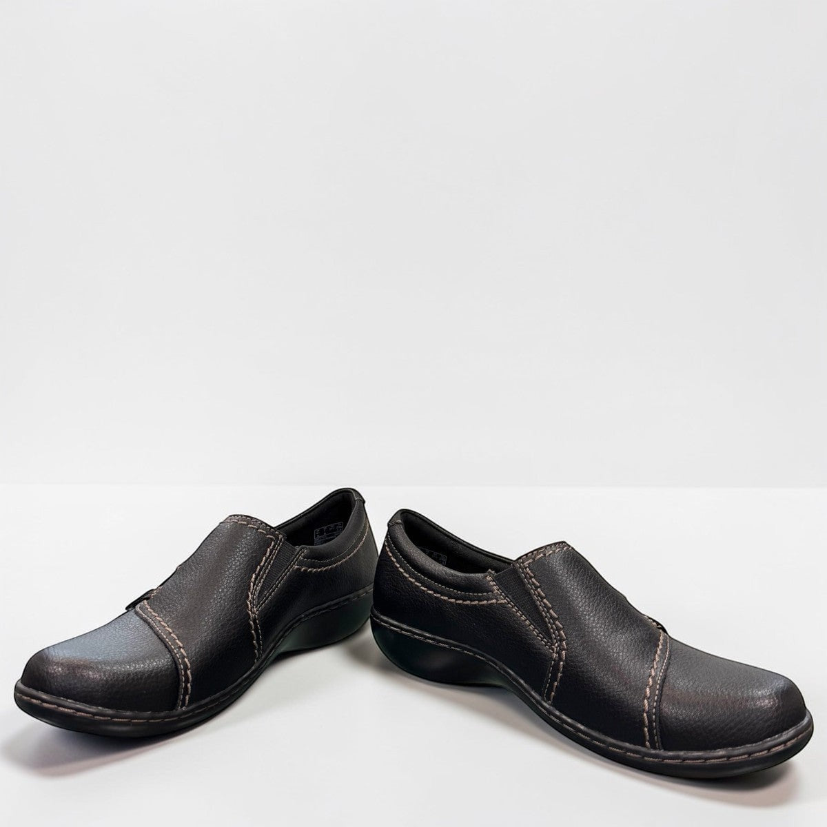 Clarks Ashland Effie black leather slip-on shoe with round toe and decorative button detail. front view.