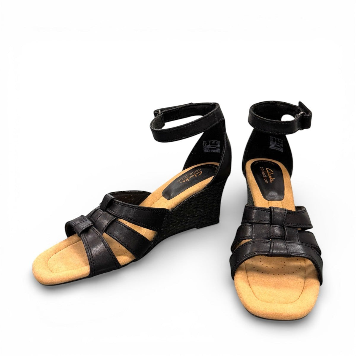 Clarks Kyarra Joy black leather wedge sandals with ankle strap and textured heel. front view.