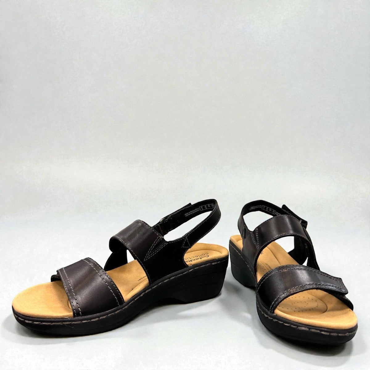 Clarks Merliah Opal black leather wedge sandals with adjustable straps and perforated detailing. front view.