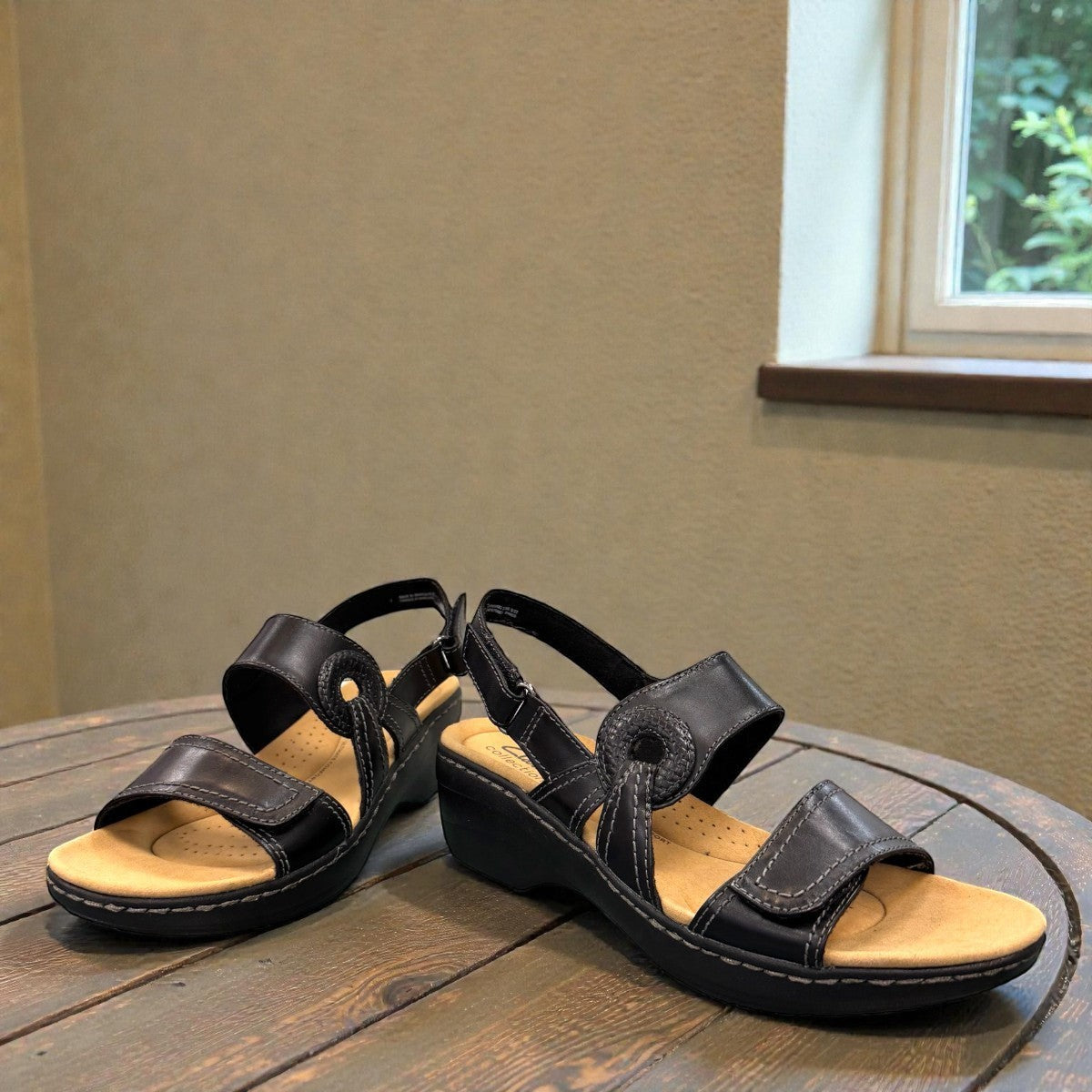 Clarks Merliah Opal black leather wedge sandals with adjustable straps and perforated detailing. front view.