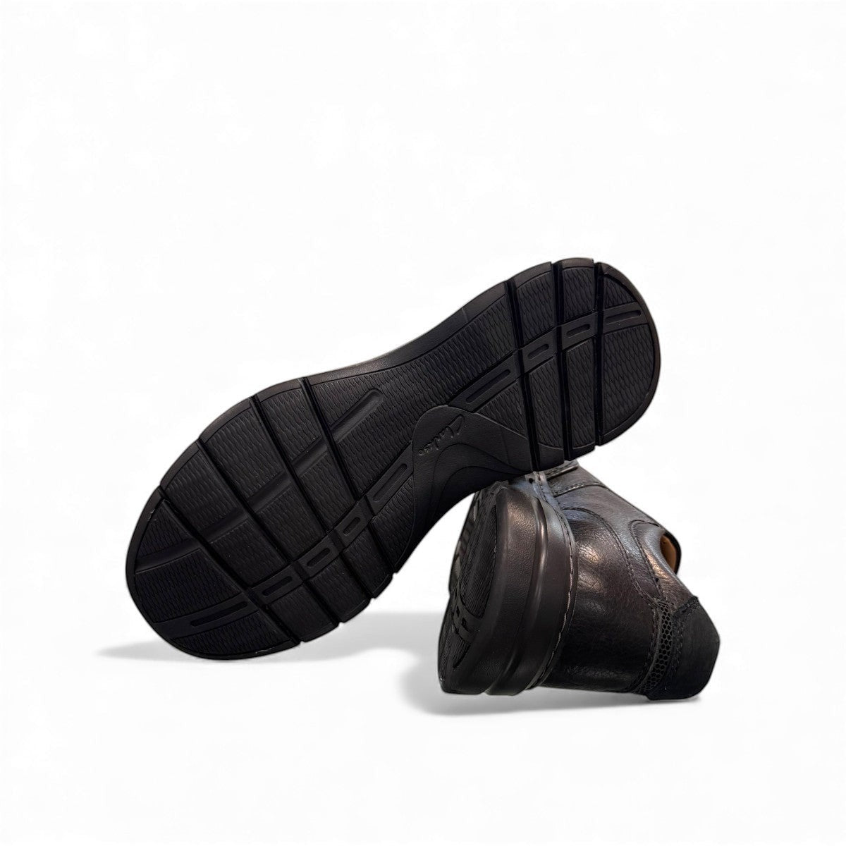Clarks Un Brawley Step black leather slip-on shoe with textured rubber sole and stitched construction. photo of the bottom.
