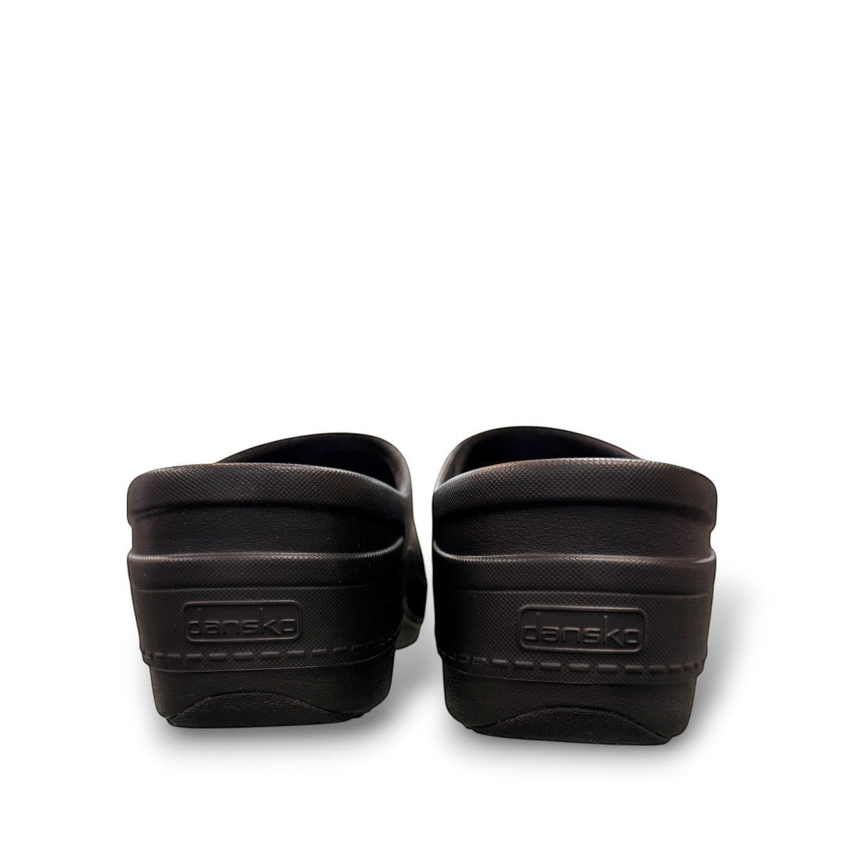Dansko Kaci black molded EVA clogs showing the slip-resistant rubber outsole tread pattern. Photo of back view.