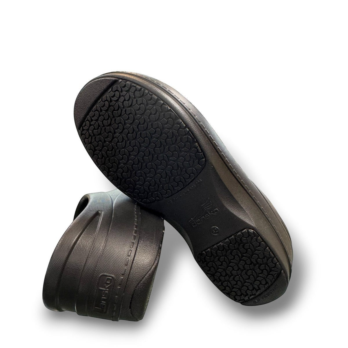 Dansko Kaci black molded EVA clogs showing the slip-resistant rubber outsole tread pattern. Photo of bottom view.