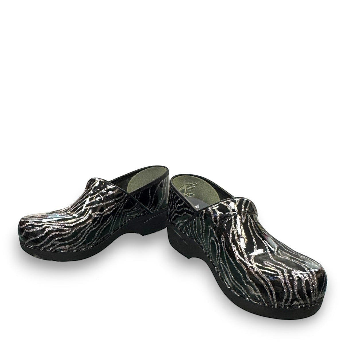 Dansko XP 2.0 patent clog showing the black slip-resistant rubber outsole and glitter wave pattern. Photo of front view at an angle.