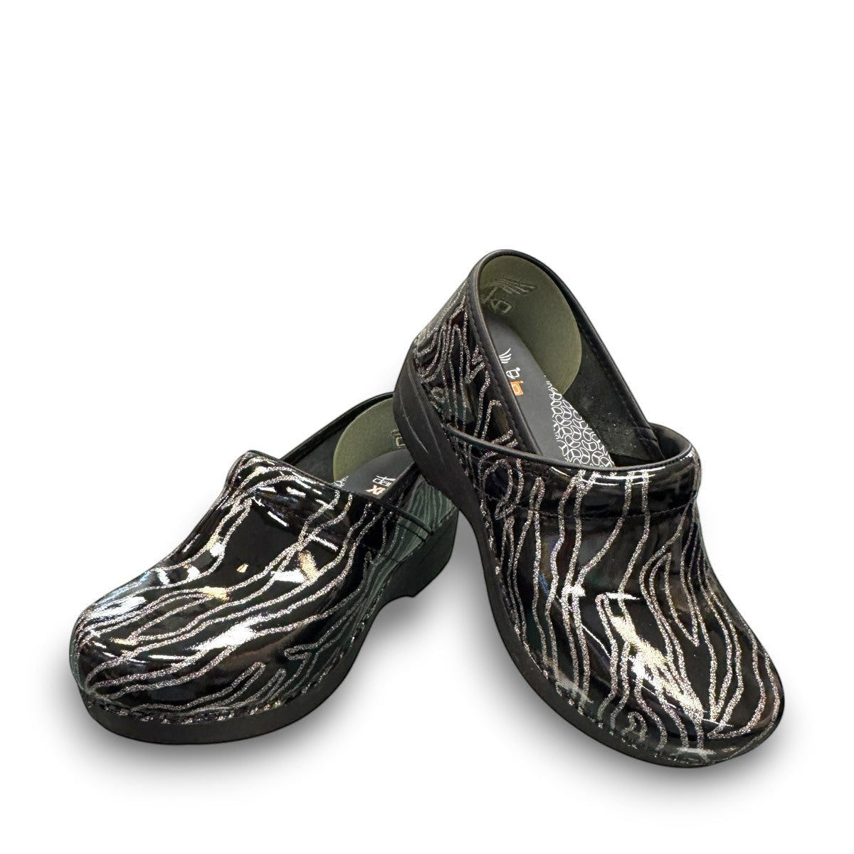Dansko XP 2.0 patent clog showing the black slip-resistant rubber outsole and glitter wave pattern. Photo of front view.