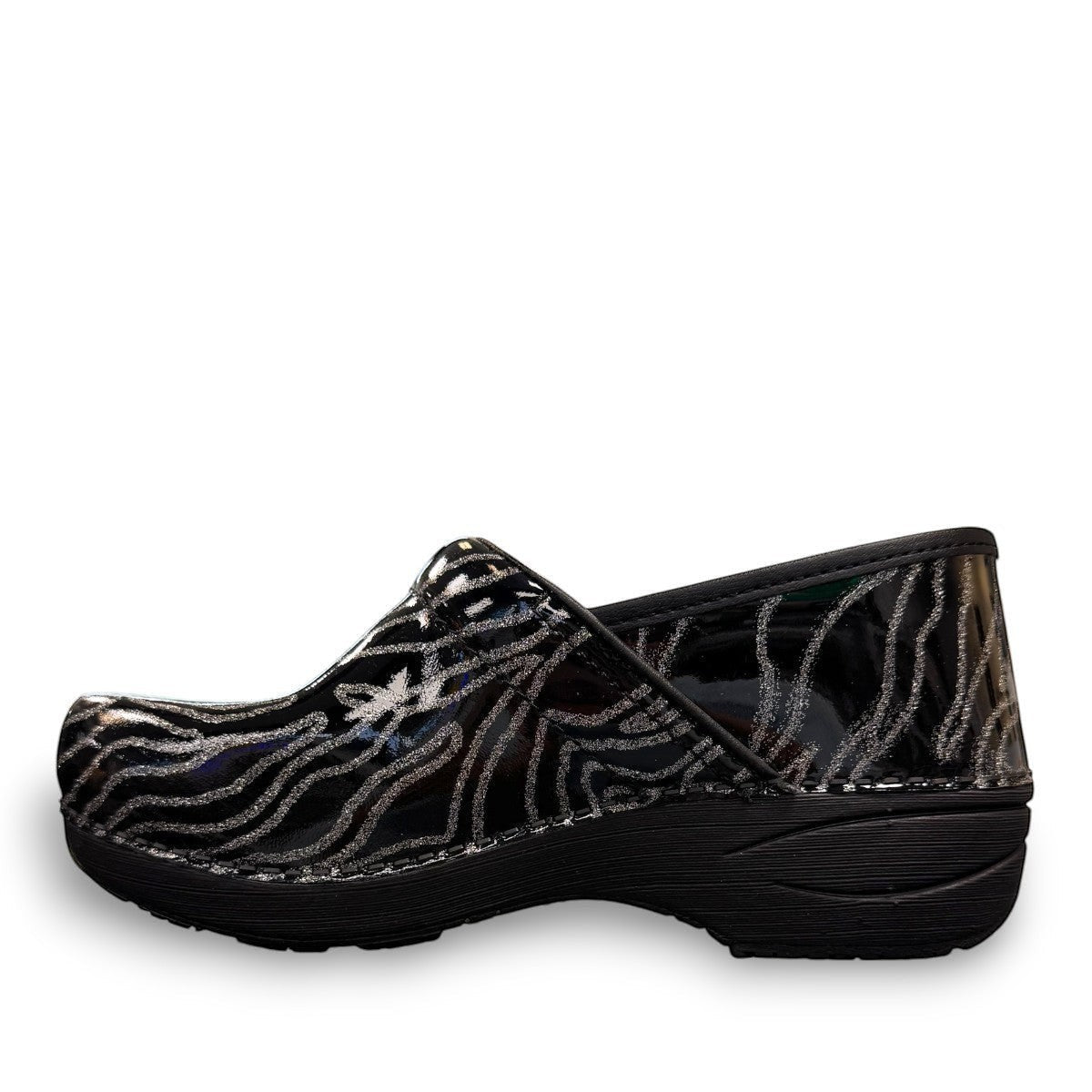 Dansko XP 2.0 patent clog showing the black slip-resistant rubber outsole and glitter wave pattern. Photo of outside left side view.