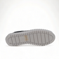 Django & Juliette black leather slip-on sneakers with perforated detail and thick white cleated sole. Photo of bottom view.