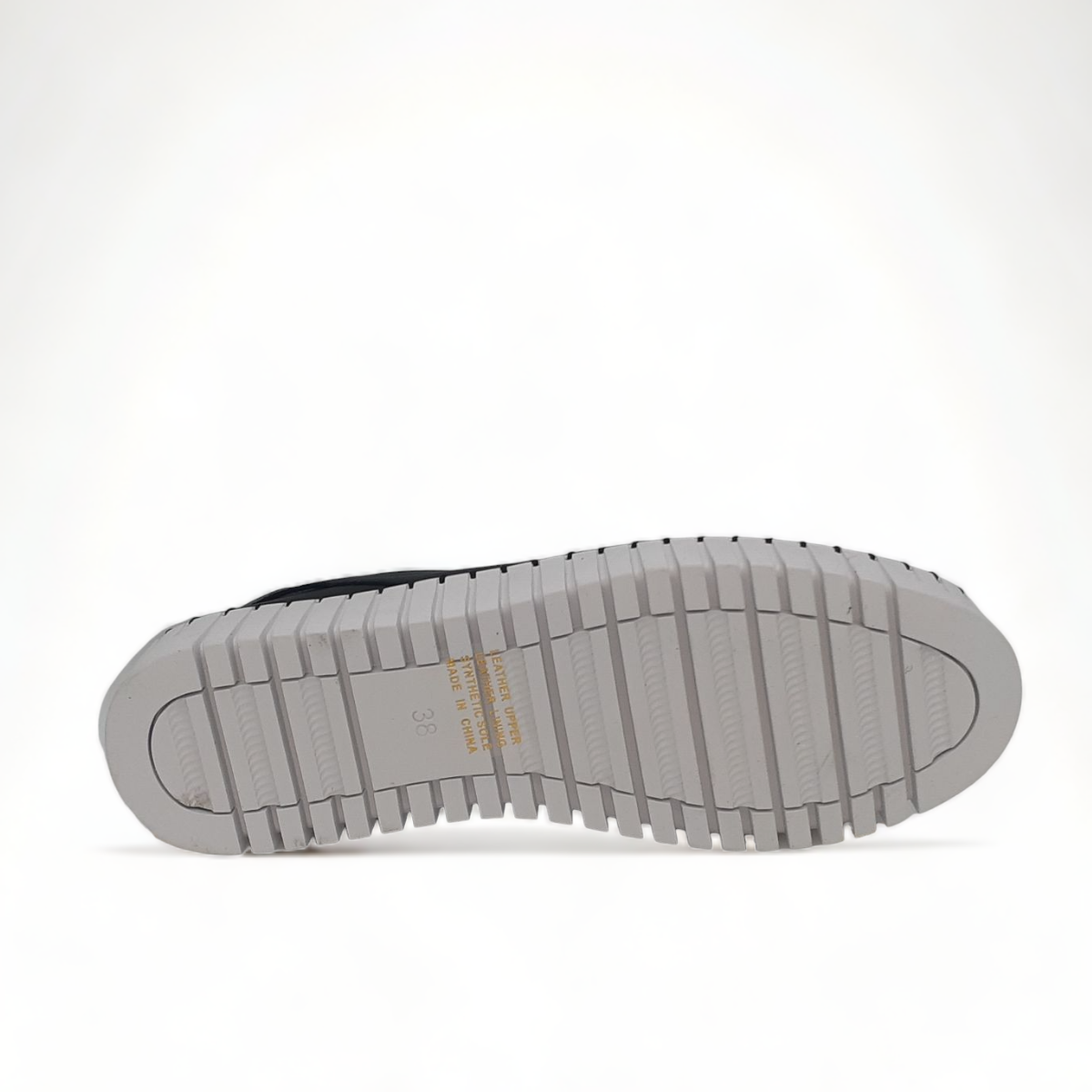 Django & Juliette black leather slip-on sneakers with perforated detail and thick white cleated sole. Photo of bottom view.
