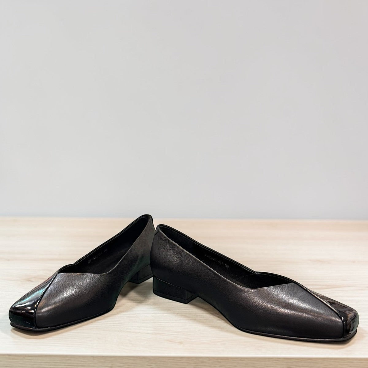 DJANGO & JULIETTE Bavari black leather slip-on heel with a glossy patent toe and low block heel. front view.