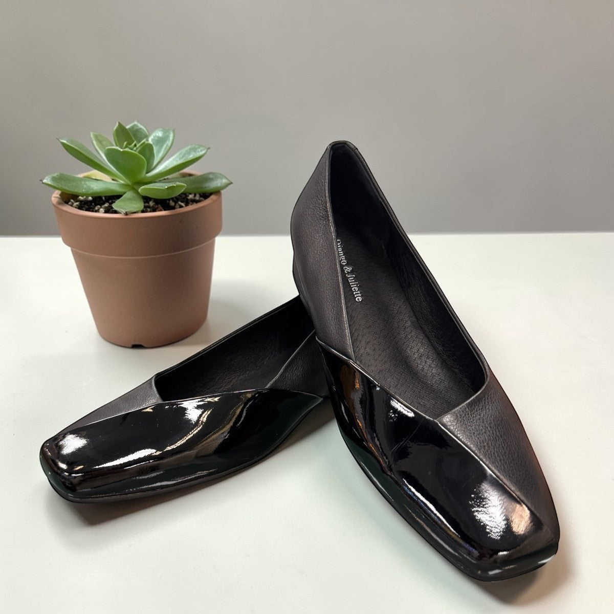 DJANGO & JULIETTE Bavari black leather slip-on heel with a glossy patent toe and low block heel. front view.