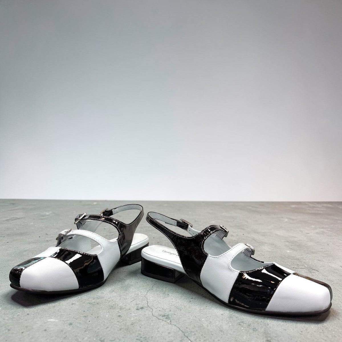 DJANGO & JULIETTE Brynns black and white patent leather slingback Mary Jane flat with buckled straps. front view.