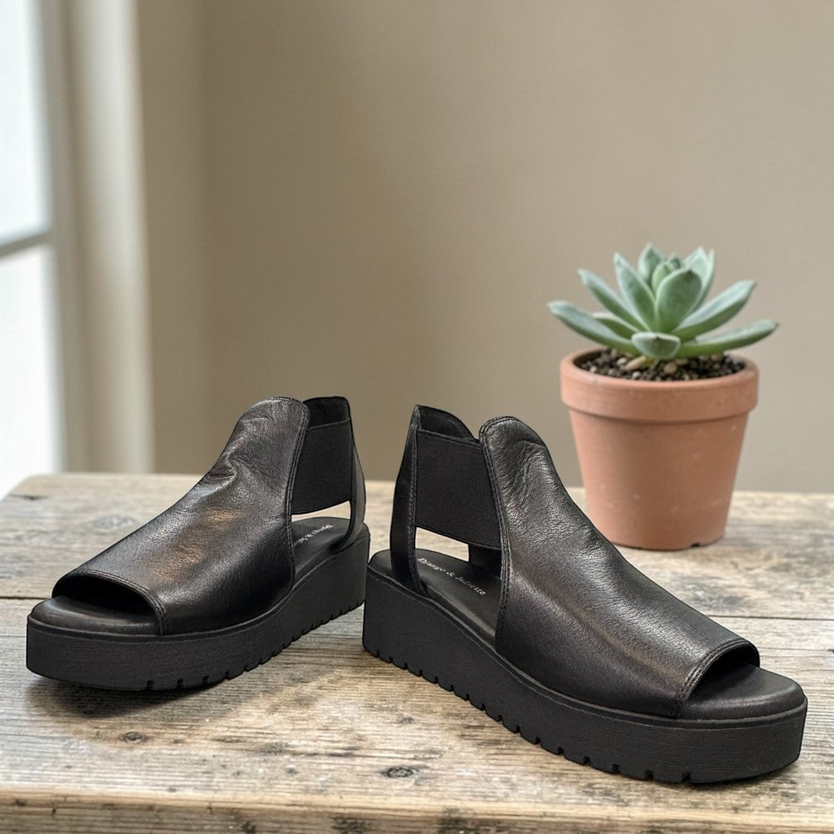 Django & Juliette Ozie black leather wedge sandal with elastic straps and a 2-inch platform sole.  front view.