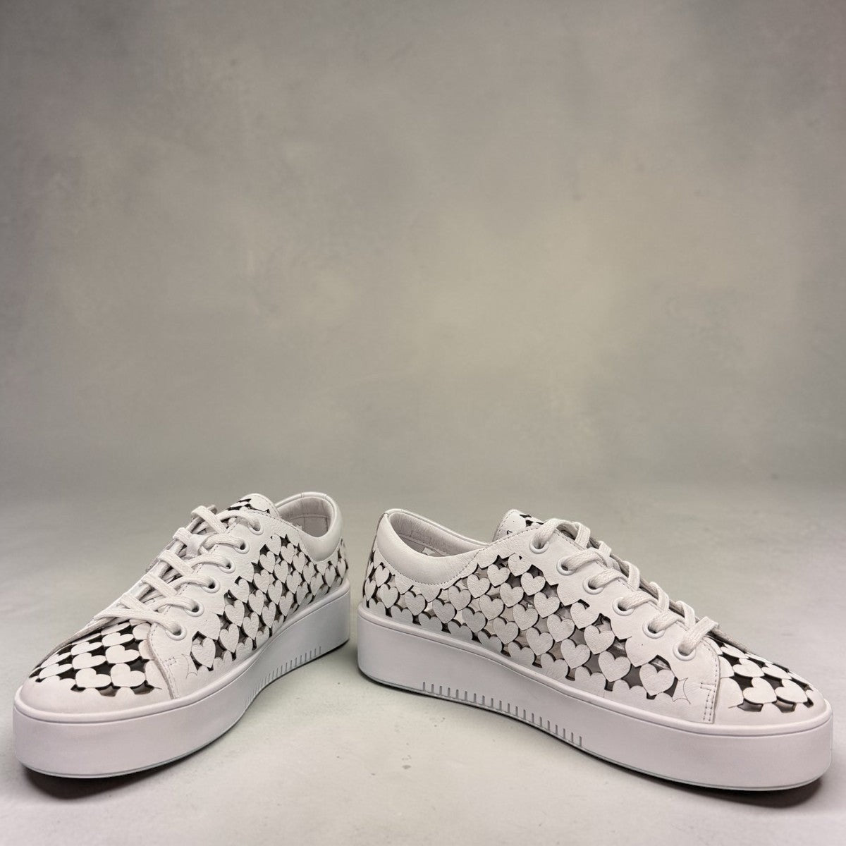 Django & Juliette white leather platform sneakers with heart-shaped laser cutouts and side zipper. front view.