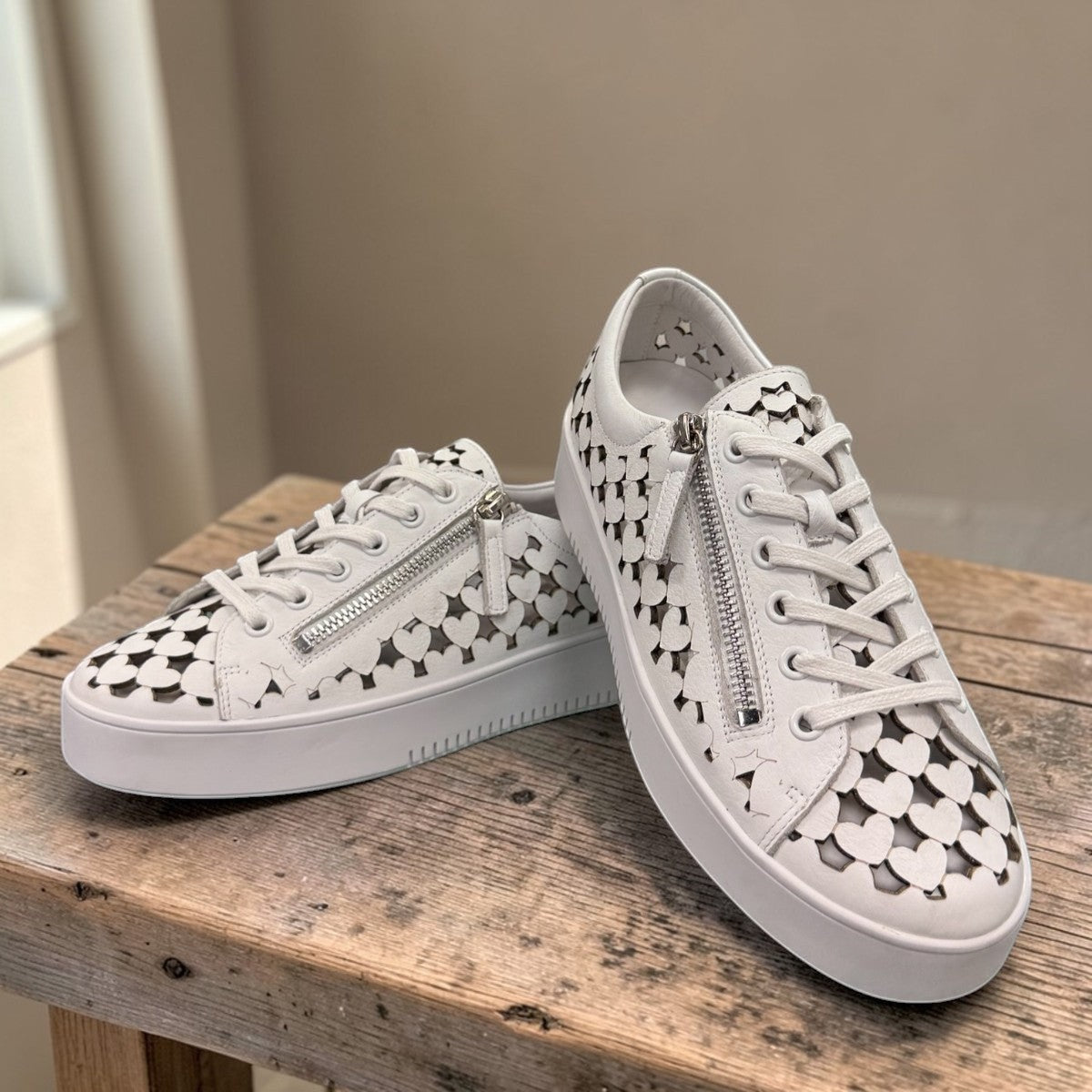 Django & Juliette white leather platform sneakers with heart-shaped laser cutouts and side zipper.front view.