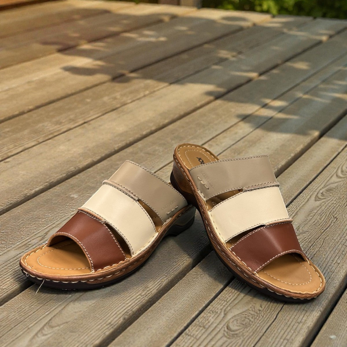 Josef Seibel Catalonia 86 cognac leather wedge sandals with multi-tone straps on a wooden deck. photo of the front.