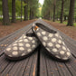 Lhasa grey wool mule slippers with white polka dots on a wooden bench in a tree-lined park