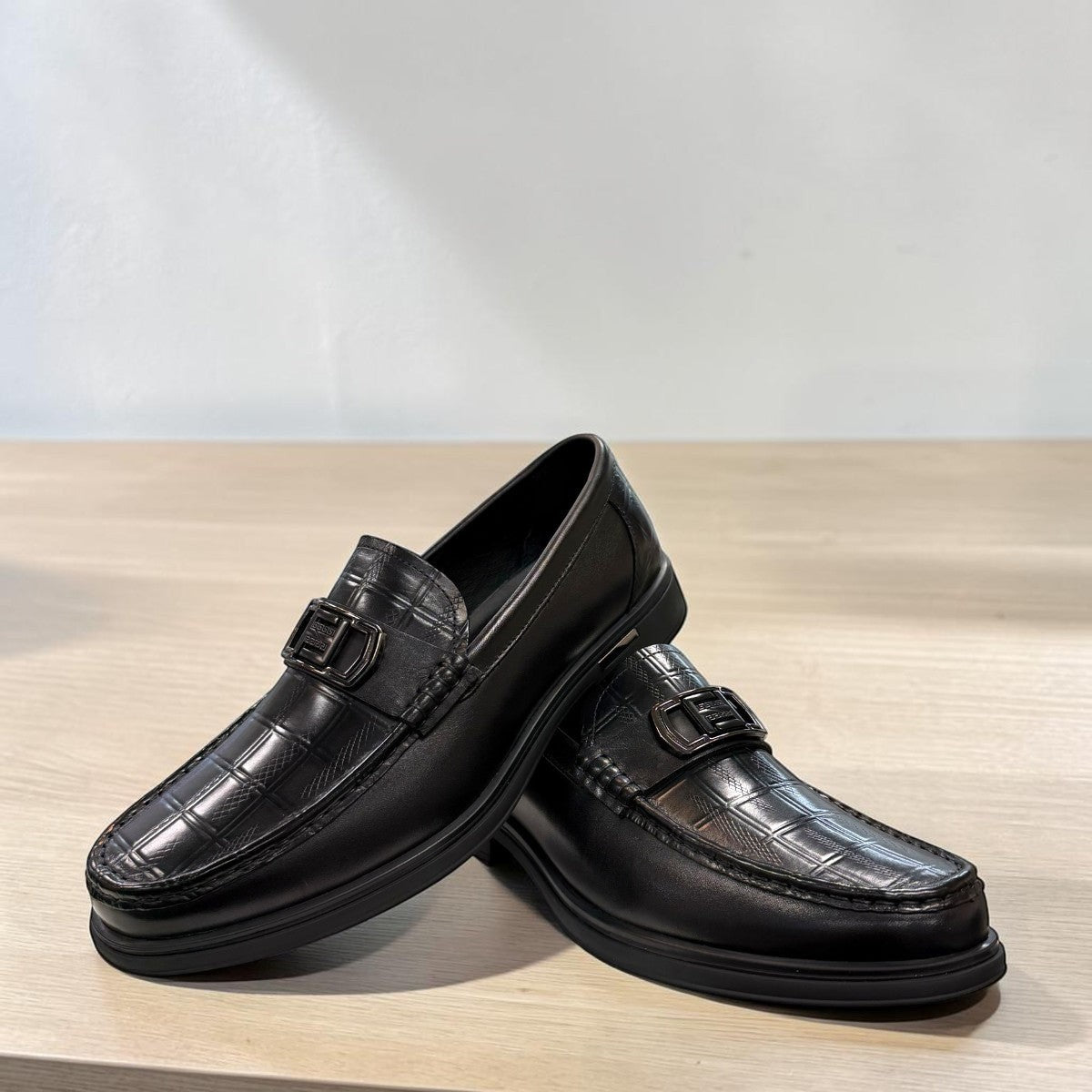Sina Footwear black genuine leather loafers with a crocodile-embossed texture and a sleek slip-on design.
photo of the front side