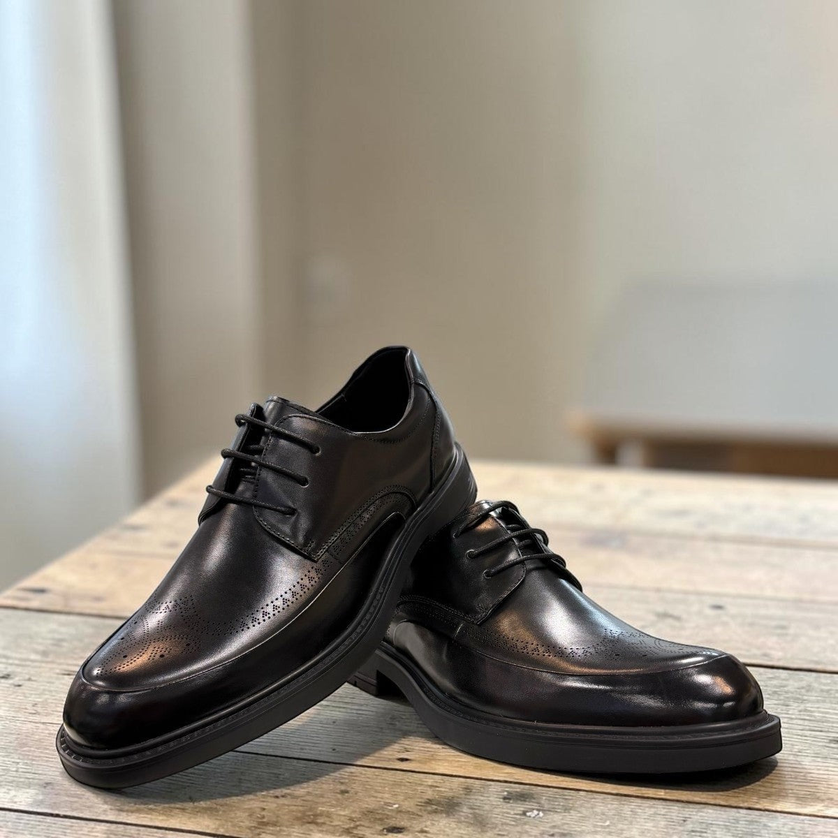 Sina Footwear black leather derby shoe with brogue-inspired perforations and a lightweight chunky rubber sole.
photo of the front side