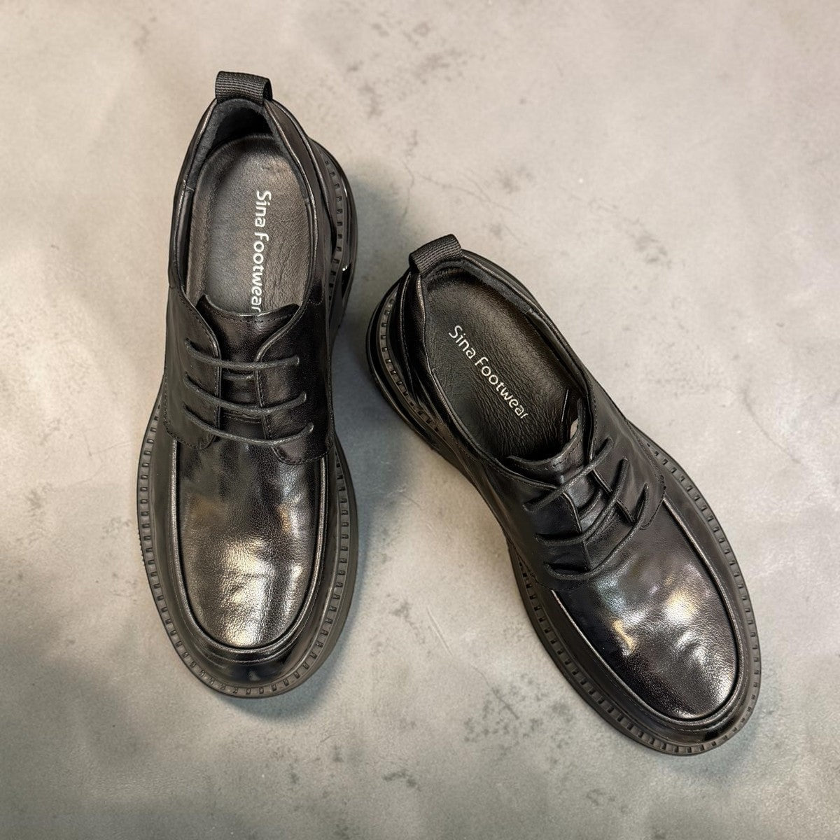 Sina Footwear black leather derby shoe with a chunky lug sole and lace-up closure in a modern silhouette.
photo of the top side