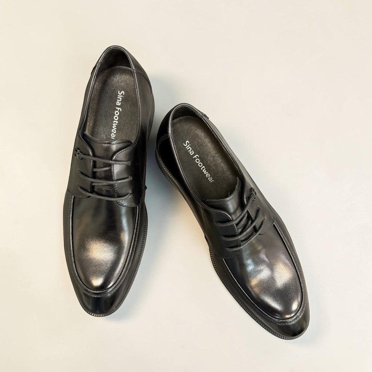 Sina Footwear black leather derby shoes with apron-toe construction, lace-up closure, and durable rubber outsole.
photo of the top side