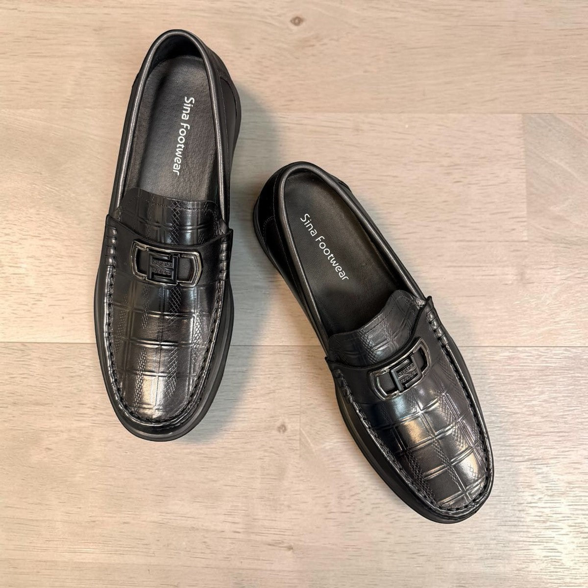 Sina Footwear black genuine leather loafers with a crocodile-embossed texture and a sleek slip-on design.
photo of the top side