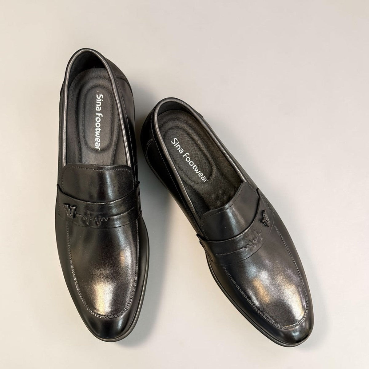 Sina Footwear black genuine leather loafer with a classic silhouette, slip-on design, and durable rubber outsole.
photo of the top side