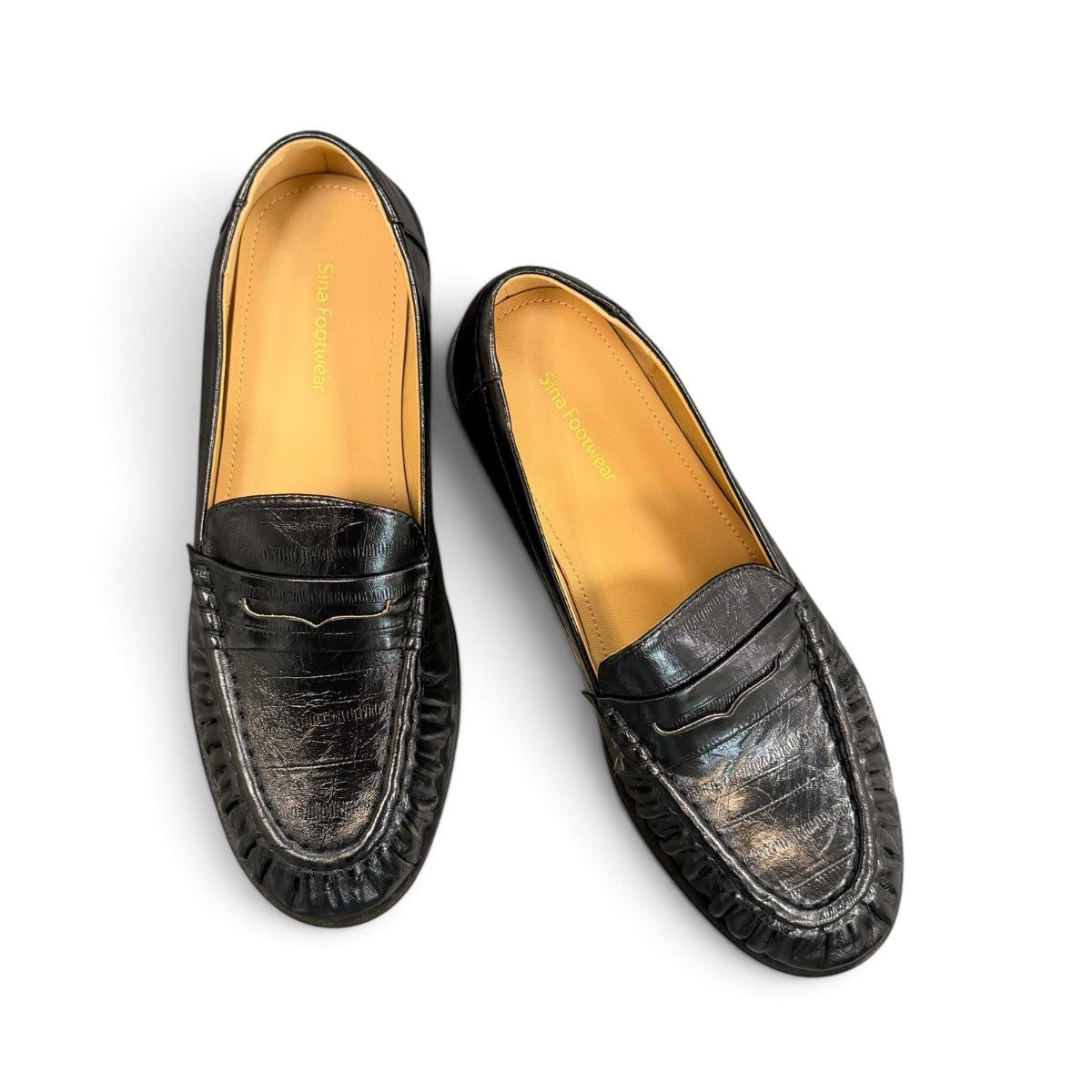 Sina Footwear black genuine leather slip-on loafer with hand-finished gathered detailing and a durable rubber outsole.
photo of the top side