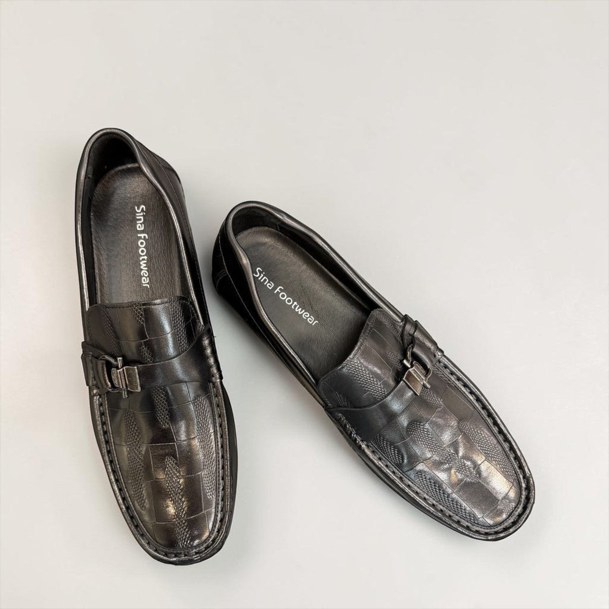 Sina Footwear black genuine leather loafer with a textured vamp strap and durable rubber outsole.
photo of the top side