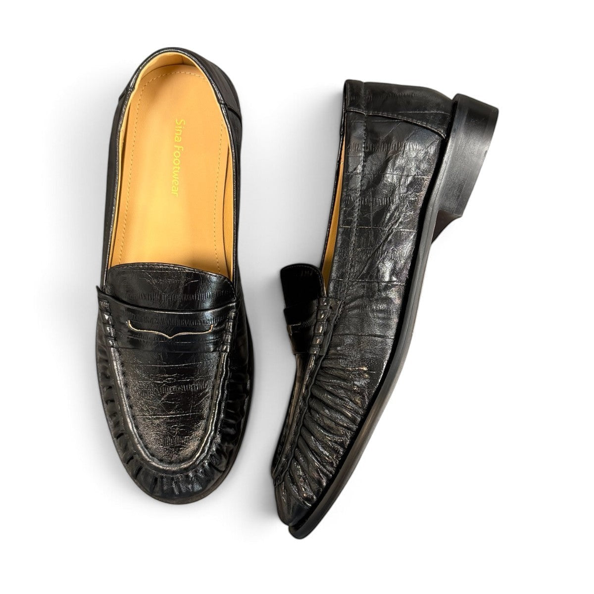 Sina Footwear black genuine leather slip-on loafer with hand-finished gathered detailing and a durable rubber outsole.
photo of the top side