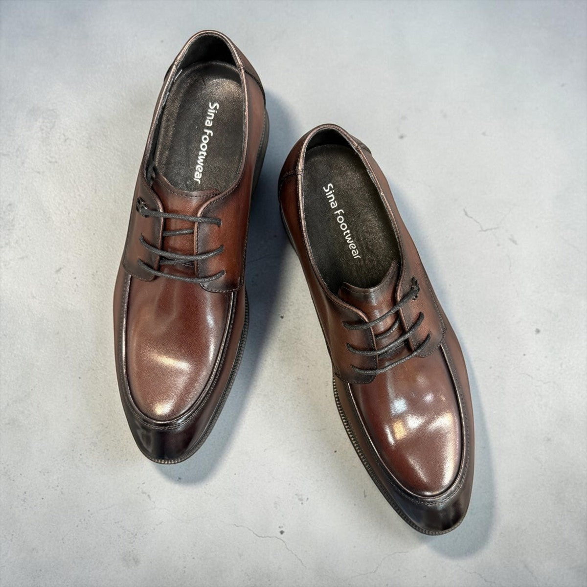 Sina Footwear dark brown leather derby shoe with apron-toe construction and lace-up design on a white background.
photo of the top side