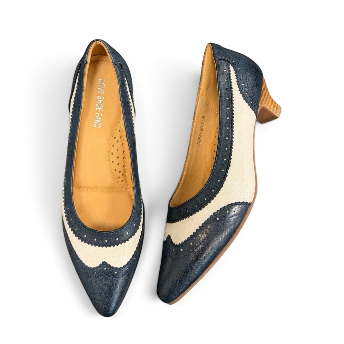 Sina Footwear navy blue and off-white leather pumps with brogue detailing, pointed toe, and low block heel.
photo of the top side