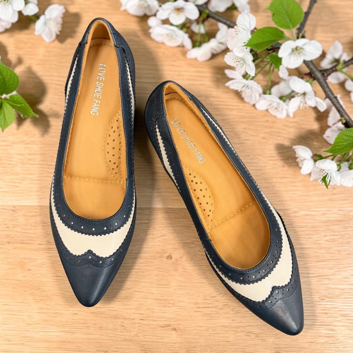 Sina Footwear navy blue and off-white leather pumps with brogue detailing, pointed toe, and low block heel.
photo of the top side