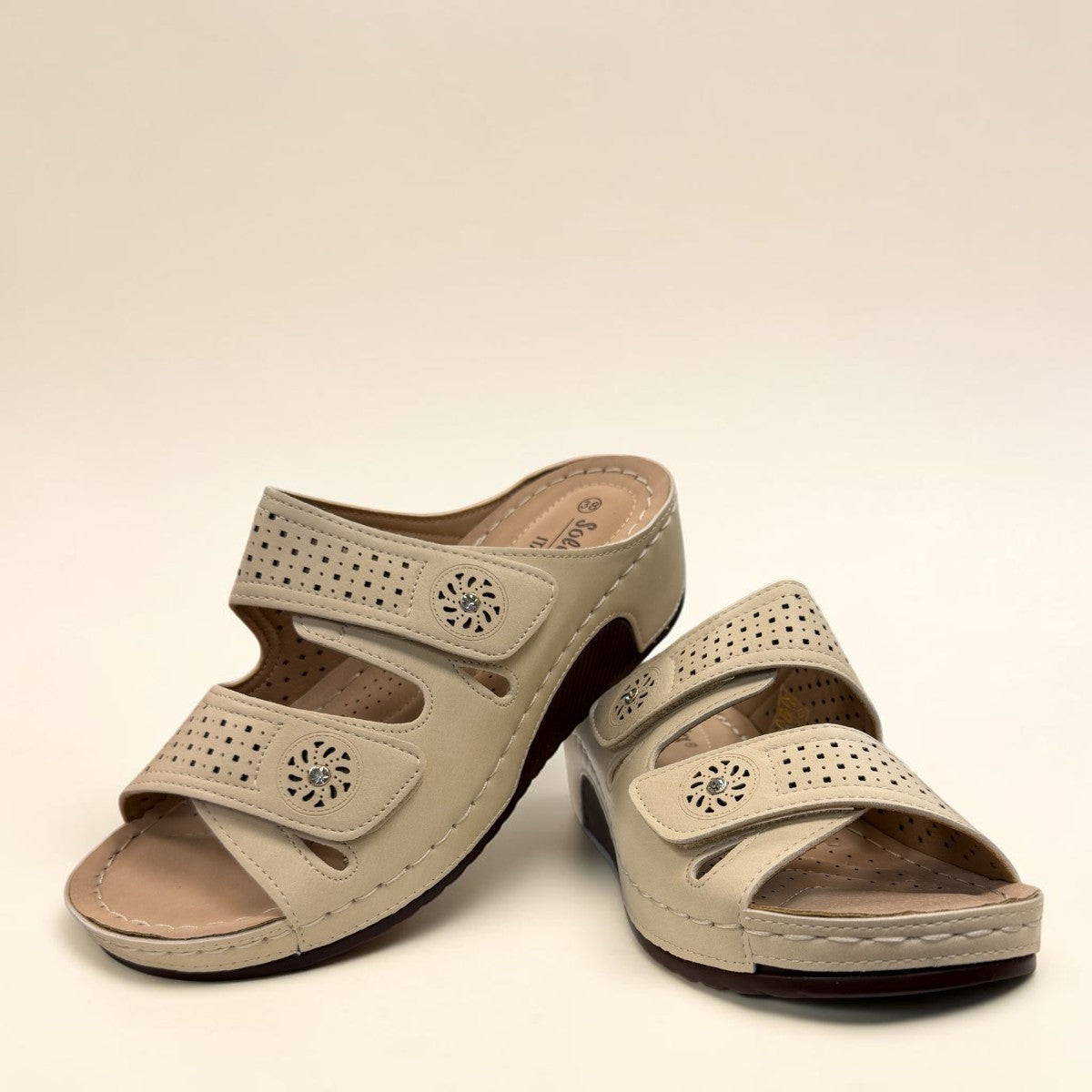 sole-flex-S1110 beige comfort slide sandals with adjustable straps, cut-out floral details, and a low wedge platform.
photo of the front side