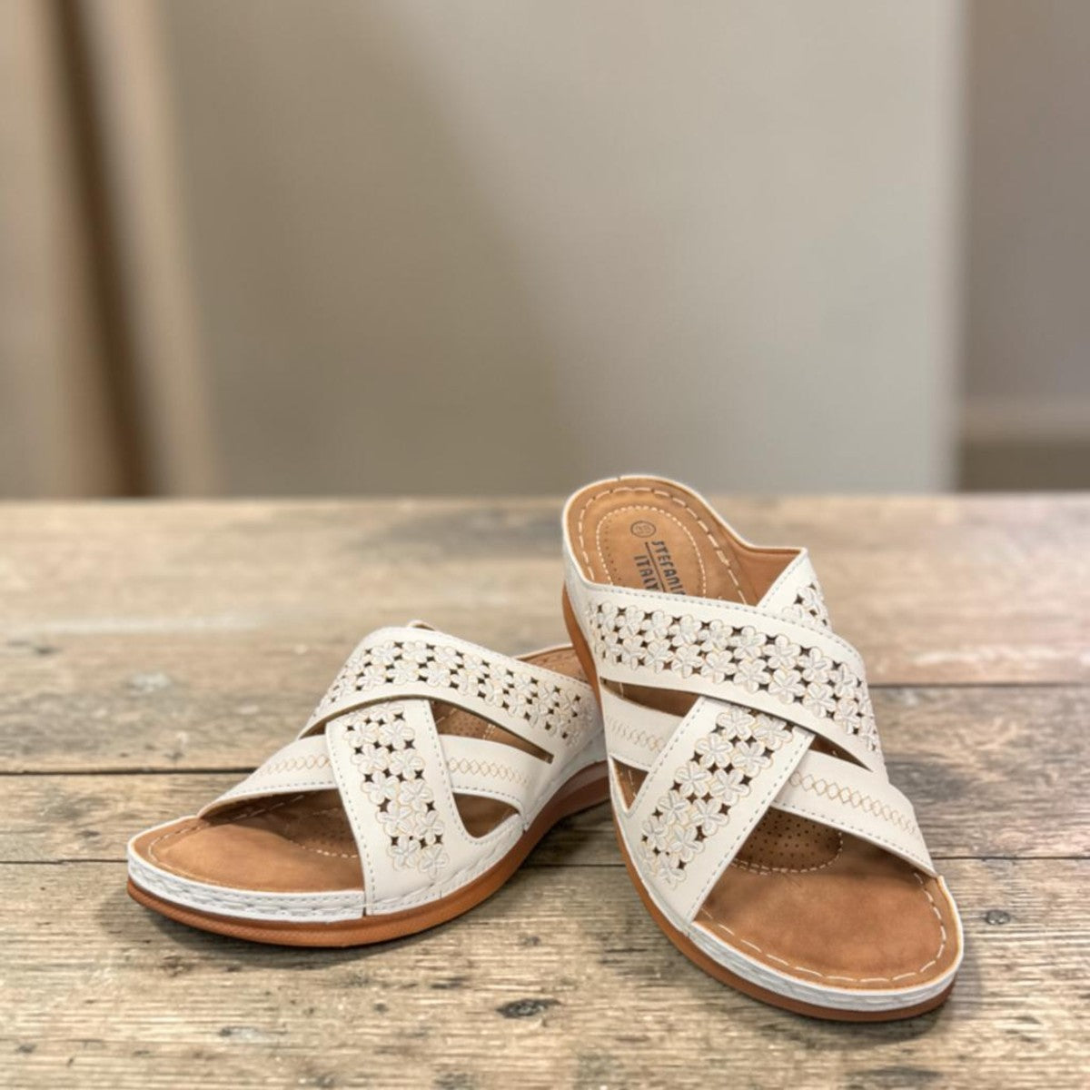 stefania S20215 white vegan leather slide sandals with floral cut-out details and a comfortable brown wedge sole.
 photo of the front side