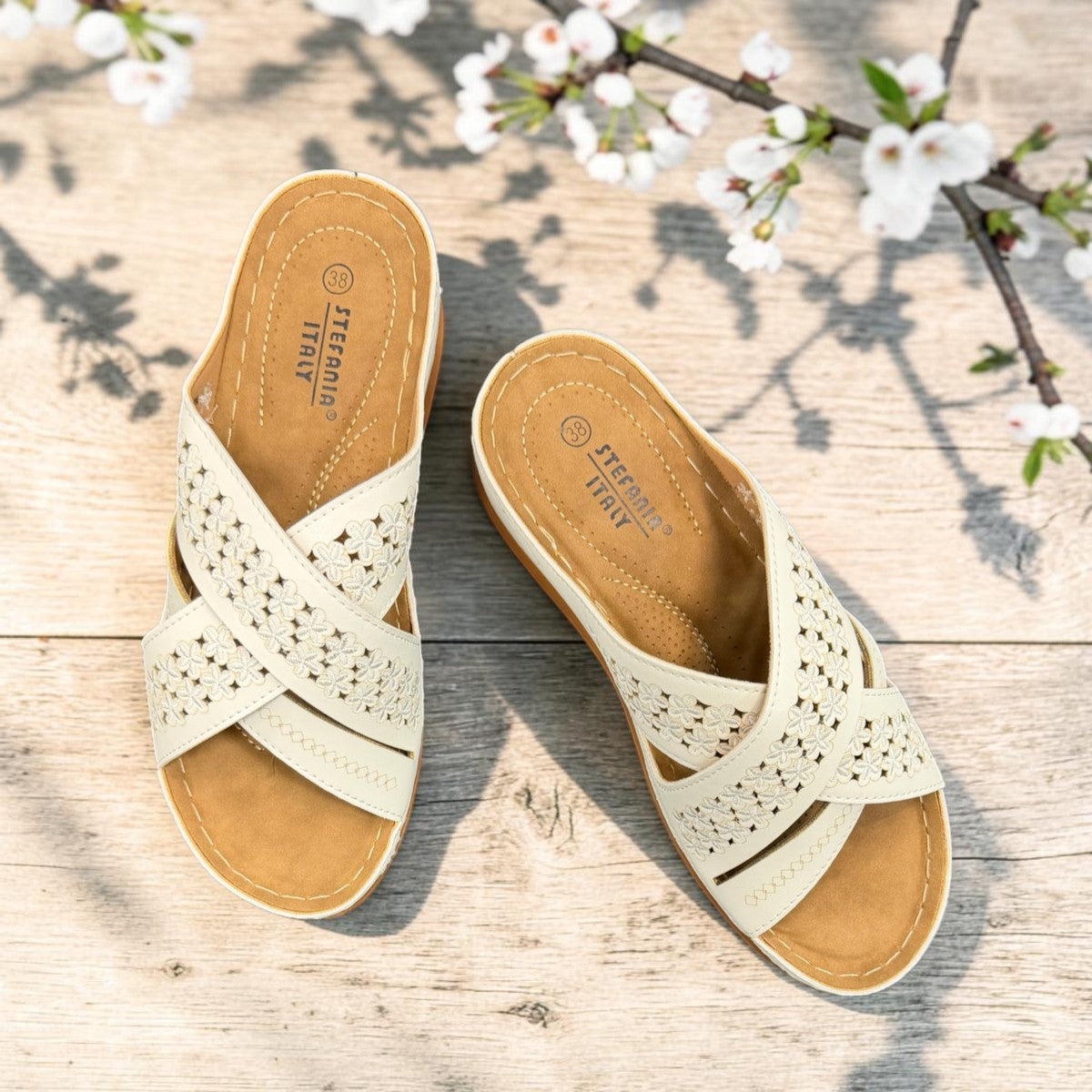 stefania S20215 white vegan leather slide sandals with floral cut-out details and a comfortable brown wedge sole.
 photo of the top side