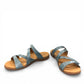 Taos Double U teal leather slide sandals with adjustable hook and loop straps and cushioned footbed. Photo of front view at an angle.