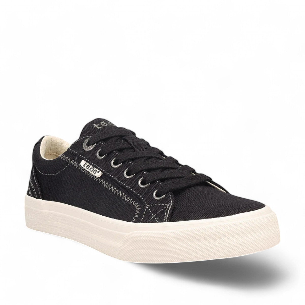 Taos Plim Soul black canvas sneaker with white rubber platform sole and decorative stitching. Photo of front view.